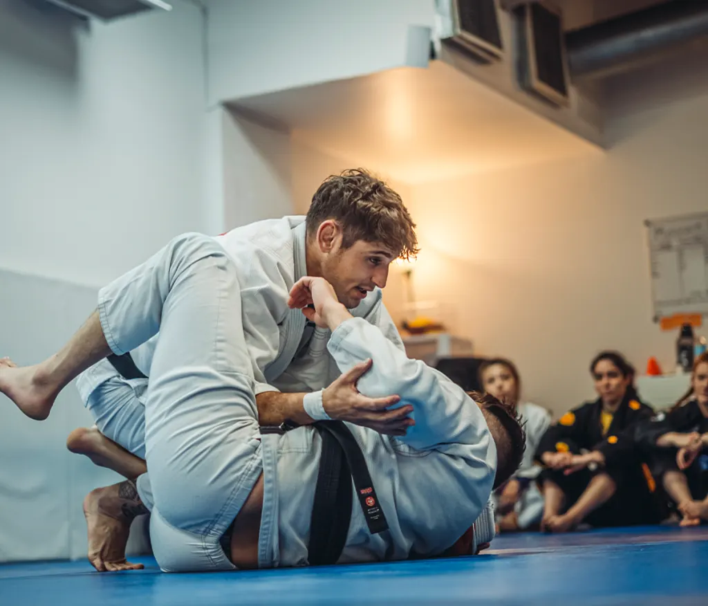 Alex demonstrating a technique while students watch from the edge of the mat