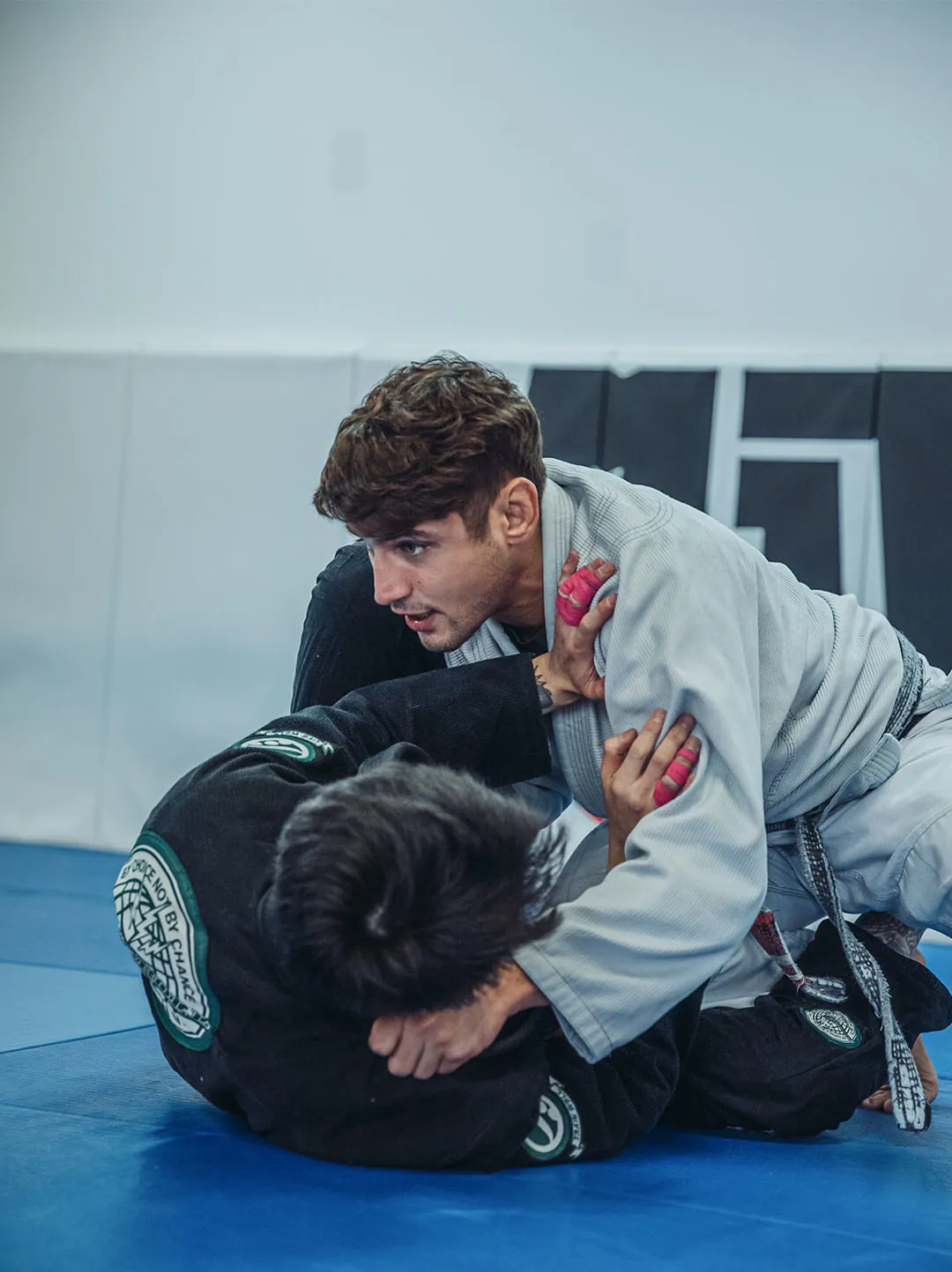 A coach passing guard during a Gi class on the blue mats at Molinaro Jiu-Jitsu