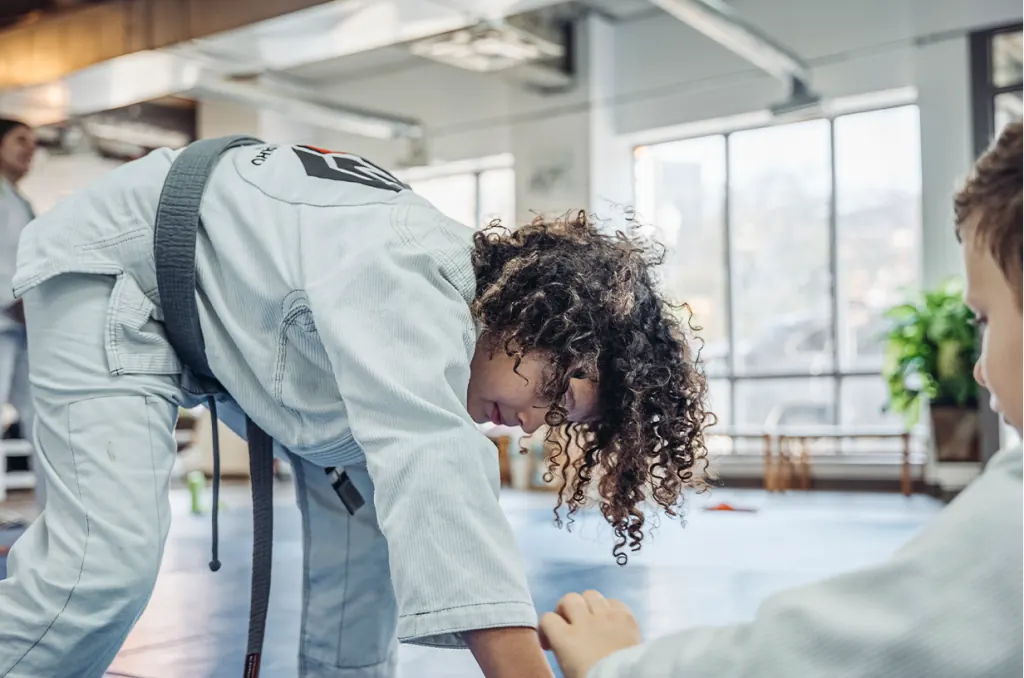 An instructor coaching a young student during kids class