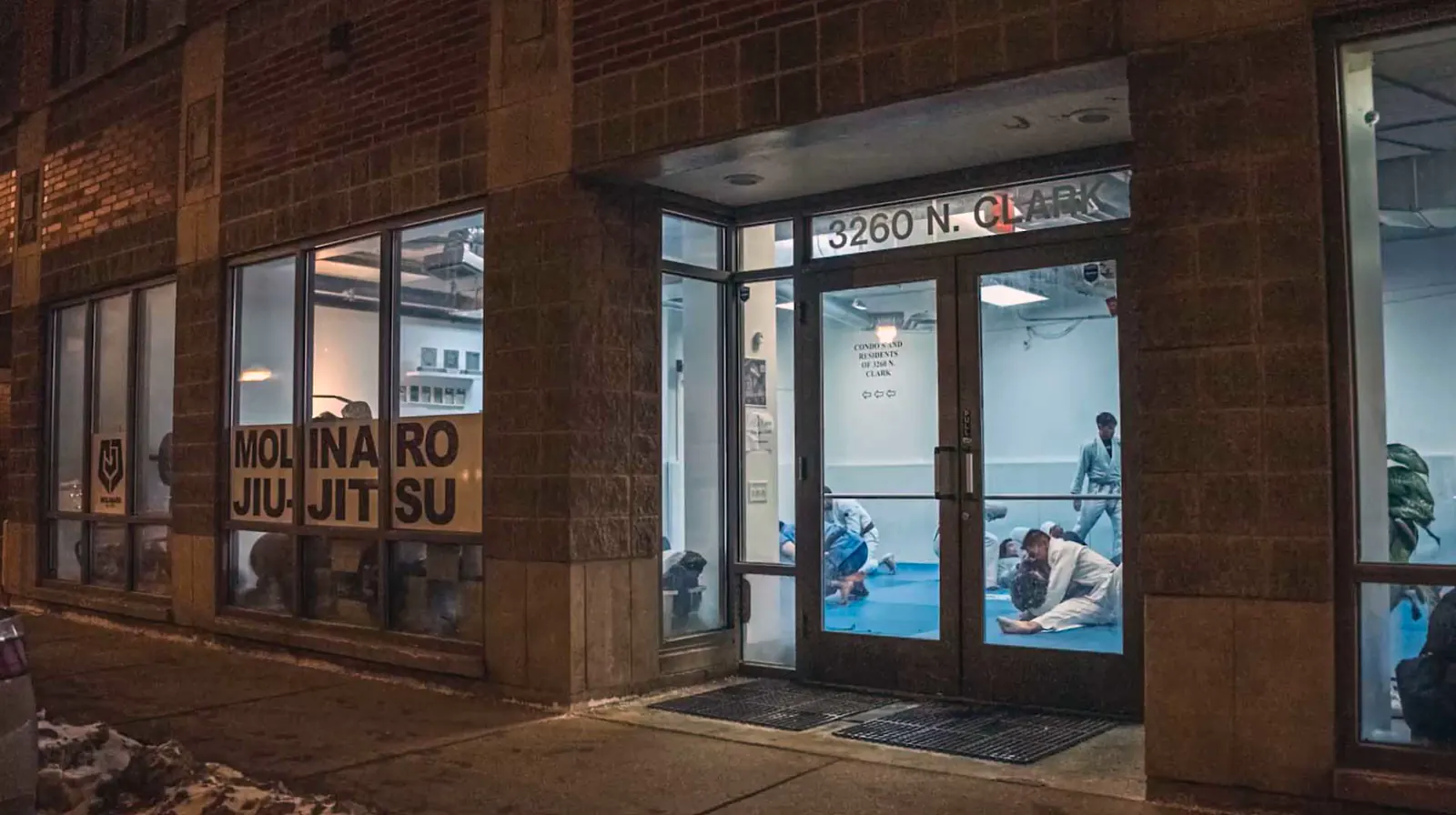 The Molinaro Jiu-Jitsu storefront at night on Clark Street, with students training inside