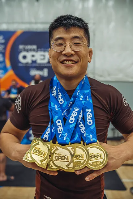 Andrew Kim holding up a handful of gold competition medals